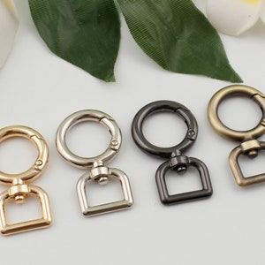 May include: Four metal swivel clasps in gold, silver, black, and bronze. Each clasp has a round ring and a square loop.