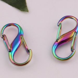 Pu&ograve; includere: Due chiusure a forma di S in metallo color arcobaleno. Le chiusure sono in metallo e hanno una finitura lucida.