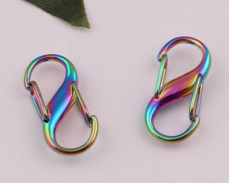 Pu&ograve; includere: Due chiusure a forma di S in metallo color arcobaleno. Le chiusure sono in metallo e hanno una finitura lucida.