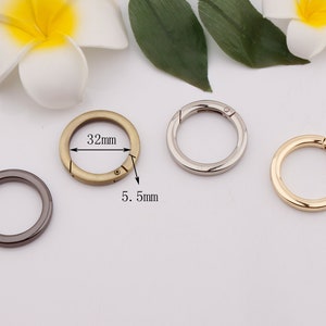 May include: Three metal key rings with a swivel clasp. The rings are 32 mm in diameter and 5.5 mm wide. The rings are in gold, silver, and black.