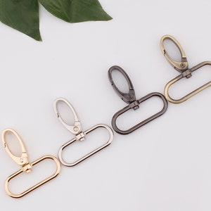 May include: Four metal swivel clasps in gold, silver, black, and antique brass finishes. The clasps are oval-shaped with a hook on one end and a loop on the other.