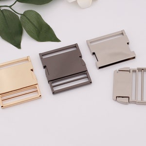 May include: Three metal slider buckles in gold, silver, and black. The buckles are rectangular with a smooth surface and two rows of holes.