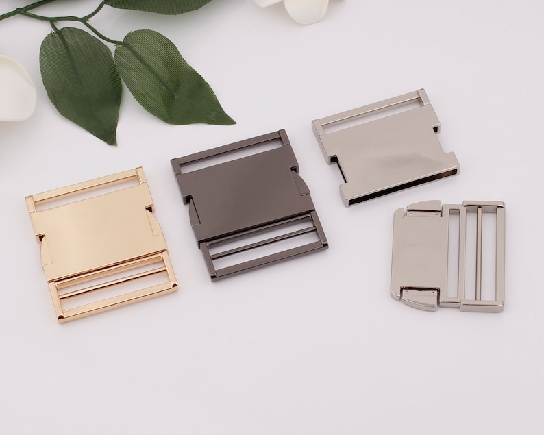 May include: Three metal slider buckles in gold, silver, and black. The buckles are rectangular with a smooth surface and two rows of holes.