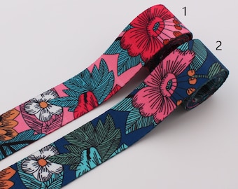 May include: Two rolls of floral patterned ribbon. One roll is pink with blue and green leaves and flowers. The other roll is blue with pink flowers and green leaves. The rolls are labeled 1 and 2.