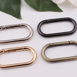 May include: Four oval-shaped metal clasps in different finishes: silver, black, gold, and antique brass. Each clasp has a spring-loaded mechanism for opening and closing.