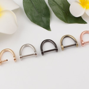 Puede incluir: Cinco anillos en D de metal en diferentes acabados: oro, plata, negro, latón antiguo y oro rosa. Los anillos son todos del mismo tamaño y tienen una barra recta que conecta los dos extremos de la forma en D.