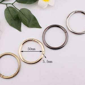 May include: Four metal key rings in different colors: gold, silver, black, and bronze. The gold ring has a measurement of 50mm in diameter and 5.5mm in width.