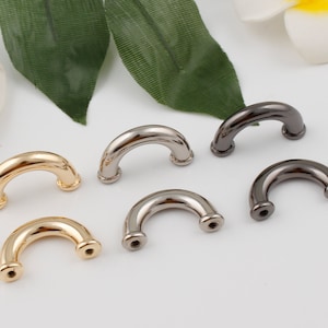 Könnte beinhalten: Sechs Metall-Handtaschengriffe in verschiedenen Ausführungen: Gold, Silber und Schwarz. Die Griffe haben alle die Form eines abgerundeten Bogens.