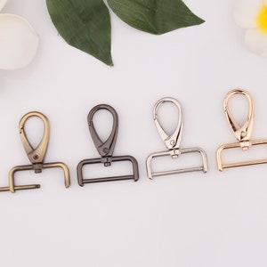 Puede incluir: Cuatro cierres giratorios de metal en diferentes acabados: dorado, negro, plateado y latón antiguo. Cada cierre tiene un bucle rectangular y una puerta de resorte.