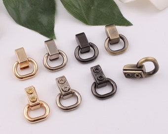 May include: Assortment of metal D-ring hardware in various finishes, including gold, silver, and black. The rings are different sizes and styles, some with screw-on closures.