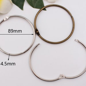 Puede incluir: Dos anillos metálicos, uno plateado y otro bronce, para encuadernar papeles u otros materiales. El anillo plateado mide 89 mm de diámetro y 4,5 mm de ancho.