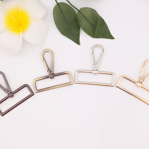 May include: Four metal swivel clasps in different finishes: antique brass, silver, gold, and black. Each clasp has a rectangular frame and a hook.