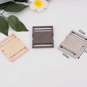 May include: Three metal buckles in gold, silver, and black. Each buckle measures 1.9 inches by 2.7 inches.