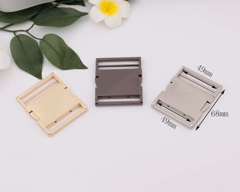 May include: Three metal buckles in gold, silver, and black. Each buckle measures 1.9 inches by 2.7 inches.