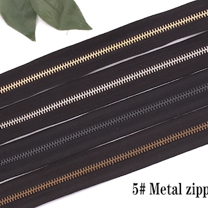 May include: Four black zipper tapes with different colored metal teeth. The teeth are gold, silver, black, and gold. The text "5# Metal zipper" is at the bottom of the image.