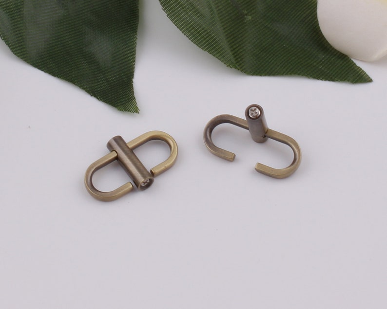 May include: Two antique gold-toned metal clasps with a swivel design. Each clasp has a small, clear rhinestone in the center.