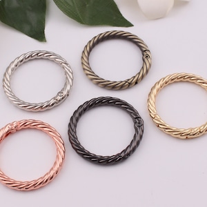 May include: Five twisted metal key rings in different finishes: silver, antique brass, black, gold, and rose gold.