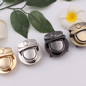 Puede incluir: Cuatro cierres metálicos de diferentes colores para bolsos o carteras. Los cierres son redondos y tienen un diseño decorativo. Los colores son dorado, plateado, negro y bronce.