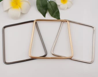 May include: Three square-shaped metal bag handles in different finishes: silver, gold, and black.
