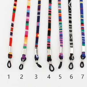 Puede incluir: Siete cadenas de gafas coloridas con cierres de metal plateado. Las cadenas est&aacute;n hechas de hilo tejido y presentan diferentes patrones y colores, incluyendo rojo, azul, verde, amarillo y morado.