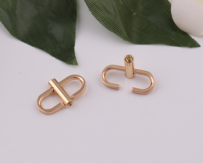 May include: Two gold-toned metal clasps with a small, round, gold-toned pin in the center of each clasp.