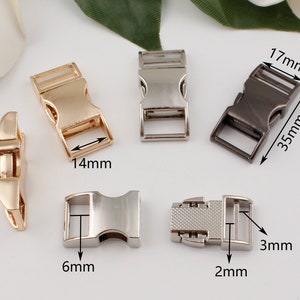Op de afbeelding: Vijf metalen gespen in verschillende maten en afwerkingen. De gespen zijn zilver, goud en zwart. De gespen zijn 17 mm x 35 mm, 14 mm, 6 mm, 2 mm en 3 mm.