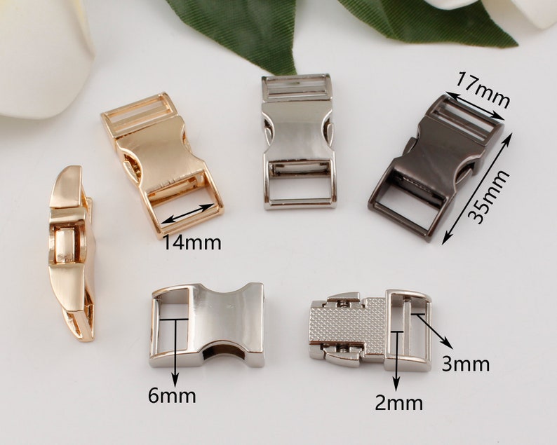 Op de afbeelding: Vijf metalen gespen in verschillende maten en afwerkingen. De gespen zijn zilver, goud en zwart. De gespen zijn 17 mm x 35 mm, 14 mm, 6 mm, 2 mm en 3 mm.