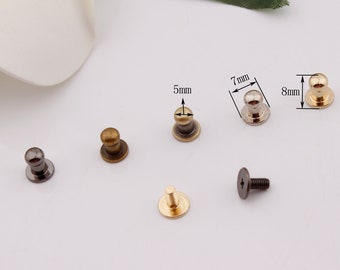 May include: A collection of metal rivets and screws in various finishes, including bronze, silver, and black. The rivets have a domed head and a flat base, with some measuring 5mm, 7mm, and 8mm in height. The screws have a flat head with a cross-shaped indentation.