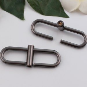 May include: Two gunmetal gray metal D-rings with a screw closure. The D-rings are about 1 inch in diameter.
