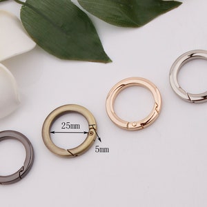 May include: Four metal key rings in different colors: silver, gold, bronze, and black. The rings are 25mm in diameter and 5mm wide.