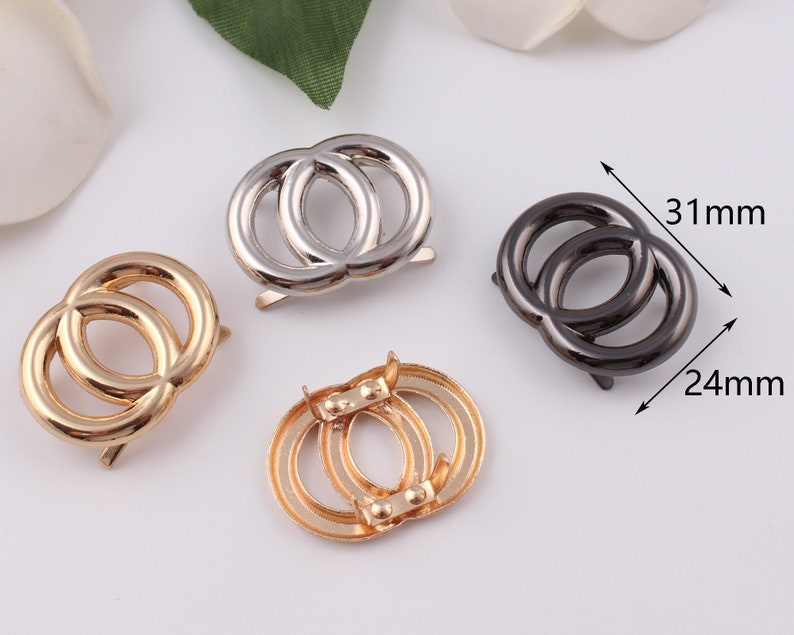 Pu&ograve; includere: Tre chiusure metalliche a doppio anello in oro, argento e nero. Le chiusure misurano circa 31 mm di larghezza e 24 mm di altezza.