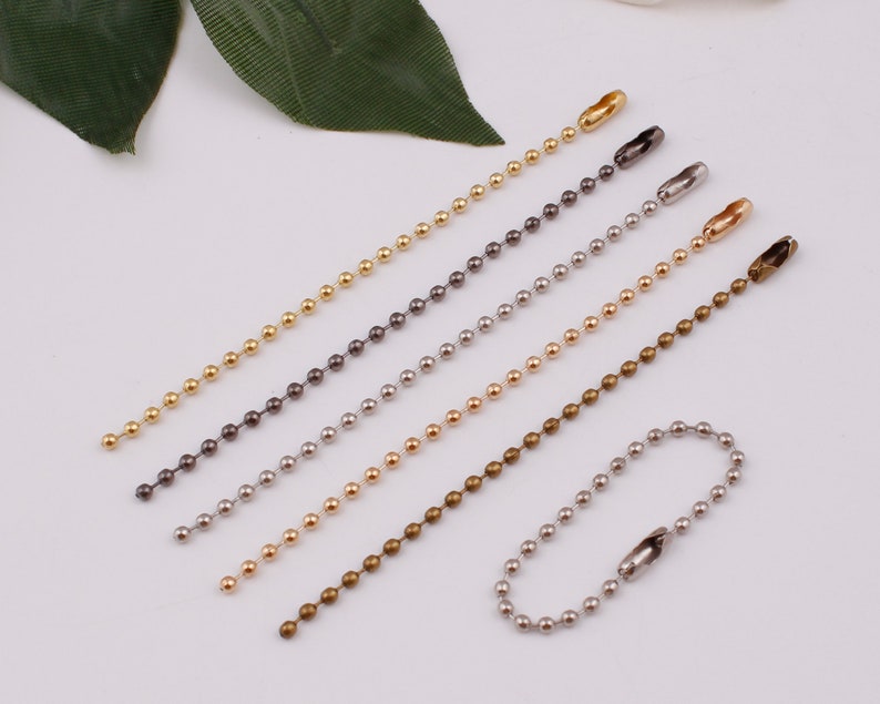 May include: Six different colored ball chain keychains with a lobster clasp. The chains are gold, silver, bronze, black, and two shades of gray.