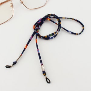 Puede incluir: Una cadena para gafas de color azul y con estampado multicolor con extremos de metal plateado. La cadena est&aacute; hecha de tejido tejido y est&aacute; dise&ntilde;ada para sujetar las gafas alrededor del cuello.