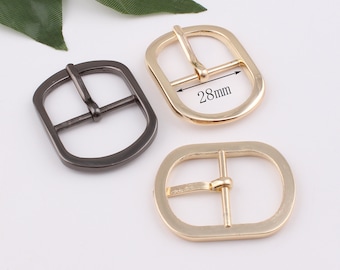 May include: Two metal belt buckles, one gold and one black, with a 28mm measurement marked on the gold buckle.