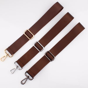 May include: Three brown adjustable straps with metal hardware. The straps have gold, silver, and black hardware.