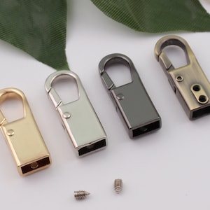 May include: Four metal swivel clasps in gold, silver, black, and antique brass finishes. The clasps are rectangular with a small loop at the top. Two small screws are also shown in the image.