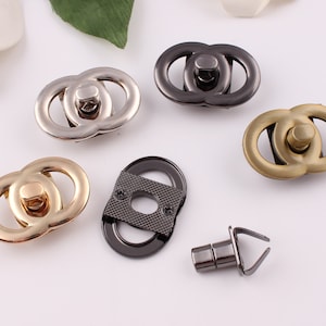 Puede incluir: Cinco cierres metálicos en diferentes acabados: dorado, plateado, negro y latón. Los cierres tienen forma de dos círculos entrelazados. También hay un poste metálico separado con un gancho.