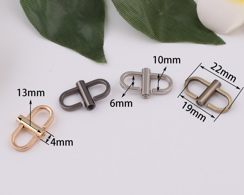 May include: Three metal D-ring clasps in different finishes: gold, silver, and black. The gold clasp measures 13mm wide and 4mm thick. The silver clasp measures 10mm wide and 6mm thick. The black clasp measures 19mm wide and 22mm long.