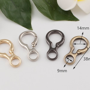 May include: Three metal keychains in gold, silver, and black. Each keychain has a 14 mm diameter ring and a 9 mm diameter loop. The keychains are 38 mm long.