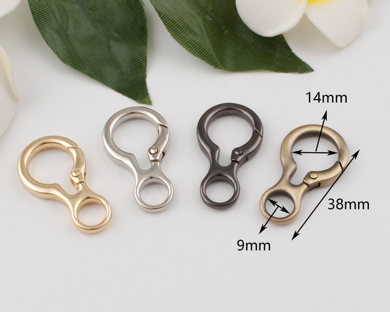 May include: Three metal keychains in gold, silver, and black. Each keychain has a 14 mm diameter ring and a 9 mm diameter loop. The keychains are 38 mm long.