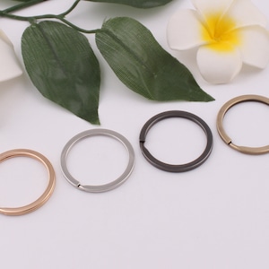 May include: Four key rings in different finishes: gold, silver, black, and bronze. The key rings are all the same size and shape.