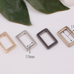 May include: Four rectangular metal buckles in gold, silver, dark grey, and antique brass. Each buckle measures 19mm long and 10mm wide. These buckles are suitable for crafting, bag making, or adding decorative elements to clothing.