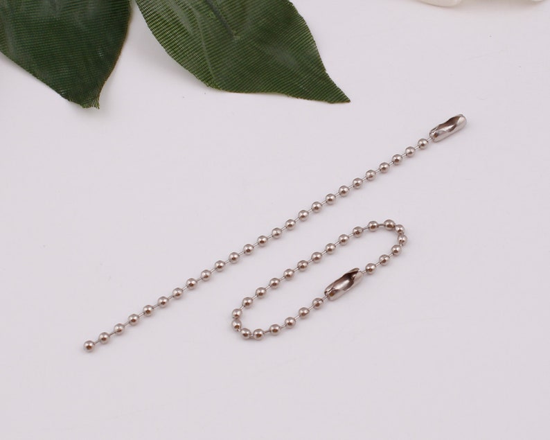 May include: A silver ball chain with a silver clasp. The chain is about 18 inches long.