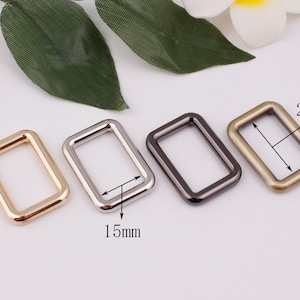 May include: Four metal rectangular rings in gold, silver, black, and bronze. The rings are 15mm and 25mm in size.