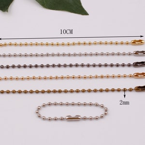 May include: Five ball chains in different colors, gold, silver, black, bronze, and silver. Each chain is 10 cm long and has a 2 mm diameter. The chains are made of metal and have a clasp at the end.