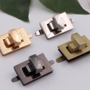 May include: Four metal clasps in different finishes: gold, silver, black, and brass. Each clasp is rectangular in shape with a small, square-shaped latch.