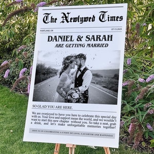 May include: A black and white newspaper style wedding announcement with the headline "The Newlywed Times" and the text "Daniel & Sarah Are Getting Married". The announcement features a black and white photo of the couple kissing in a road setting.