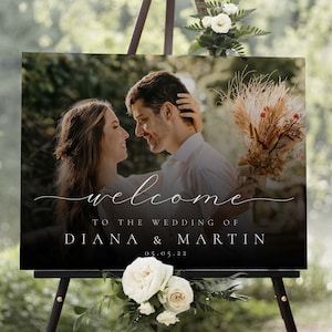 May include: A black welcome sign with a photo of a couple in front of a blurred background. The text reads "Welcome to the wedding of Diana & Martin 05.05.22".