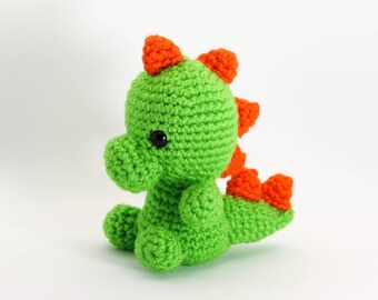 May include: A green crocheted dinosaur toy with orange spikes and black eyes.