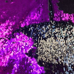 May include: A close-up of a fabric with purple and silver sequins. The sequins are arranged in a pattern that creates a gradient effect.